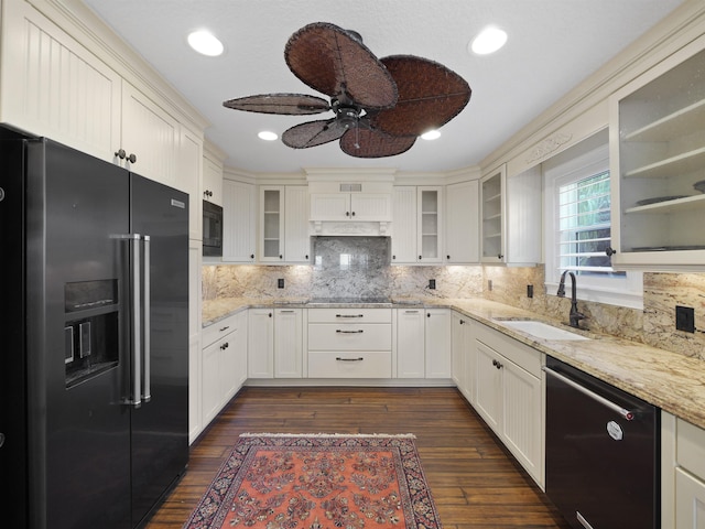 kitchen featuring black appliances, light stone counters, dark hardwood / wood-style flooring, and sink