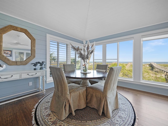 dining room featuring a wealth of natural light, dark hardwood / wood-style flooring, a water view, and ceiling fan