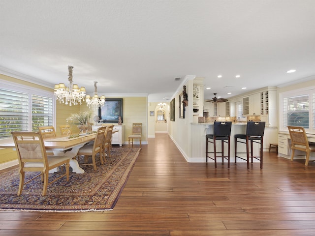 dining space featuring dark hardwood / wood-style floors, ornamental molding, and ceiling fan with notable chandelier