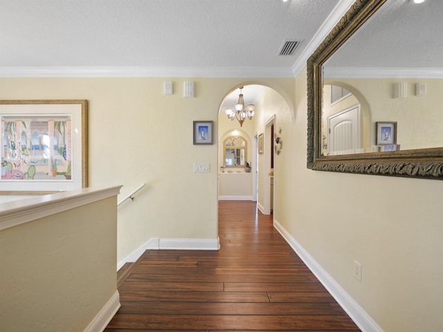 corridor featuring dark hardwood / wood-style floors, ornamental molding, a textured ceiling, and a chandelier