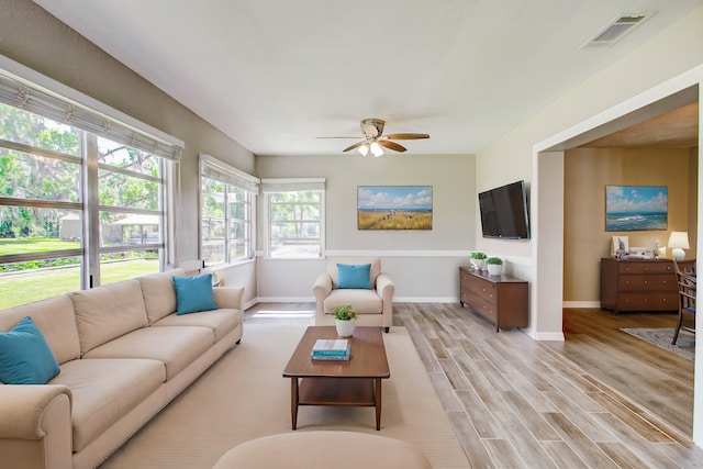 living room with light wood-type flooring, baseboards, visible vents, and ceiling fan