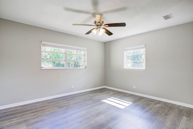 unfurnished room featuring wood finished floors, a ceiling fan, and baseboards