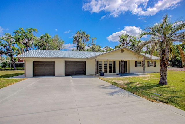 ranch-style house with metal roof, concrete driveway, brick siding, an attached garage, and a front yard