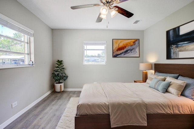 bedroom with wood finished floors, visible vents, a ceiling fan, and baseboards