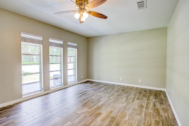 spare room featuring baseboards, wood finished floors, and visible vents
