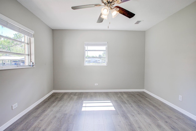 empty room with ceiling fan, baseboards, wood finished floors, and visible vents