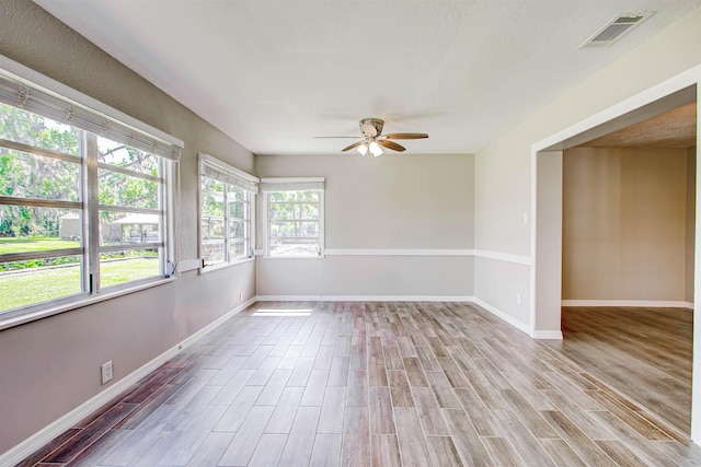 unfurnished room with light wood-type flooring, visible vents, baseboards, and ceiling fan