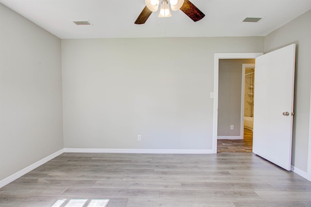 spare room featuring light wood finished floors, visible vents, a ceiling fan, and baseboards