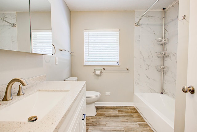 bathroom featuring toilet, bathtub / shower combination, baseboards, wood finished floors, and vanity