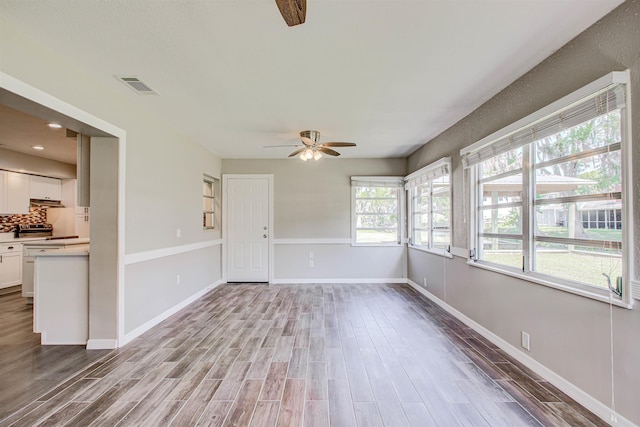 spare room with baseboards, a ceiling fan, visible vents, and light wood-type flooring