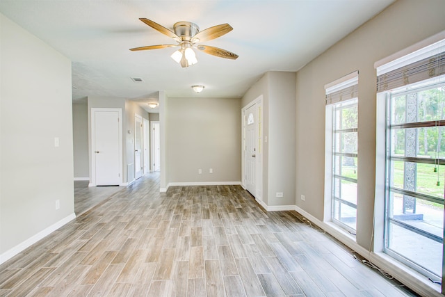 empty room featuring light wood-type flooring, visible vents, baseboards, and ceiling fan