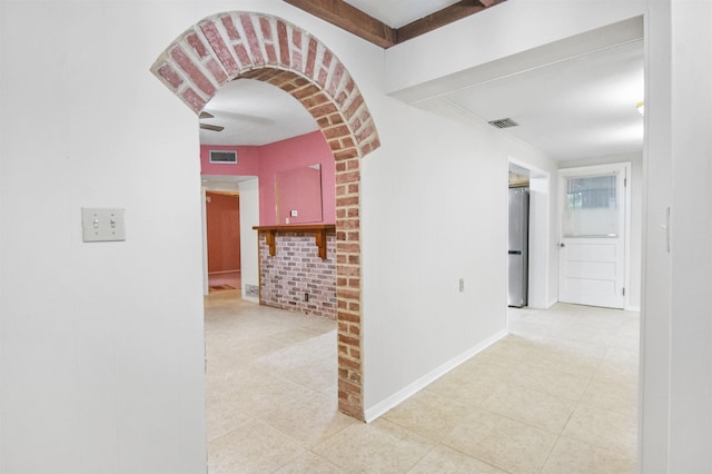 corridor featuring light tile patterned floors and brick wall