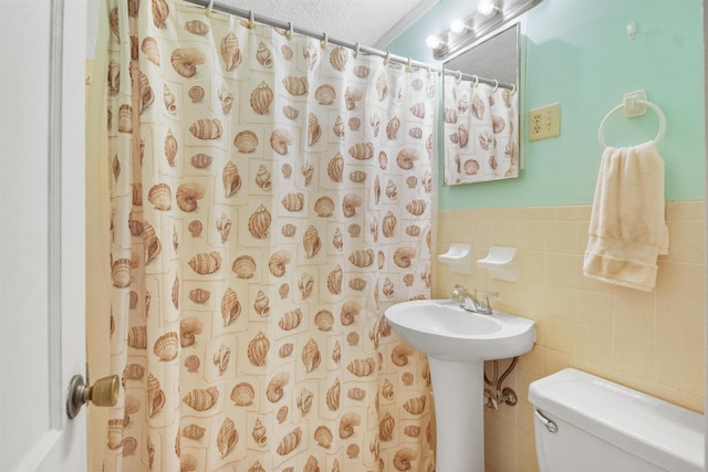 bathroom featuring a shower with curtain, tile walls, a textured ceiling, and toilet