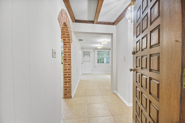 hallway with light tile patterned floors and beam ceiling