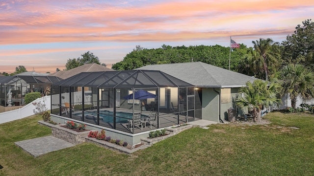 back of property at dusk featuring a patio, stucco siding, a fenced backyard, a yard, and a fenced in pool