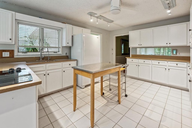 kitchen featuring sink, light tile patterned floors, ceiling fan, white cabinetry, and a textured ceiling