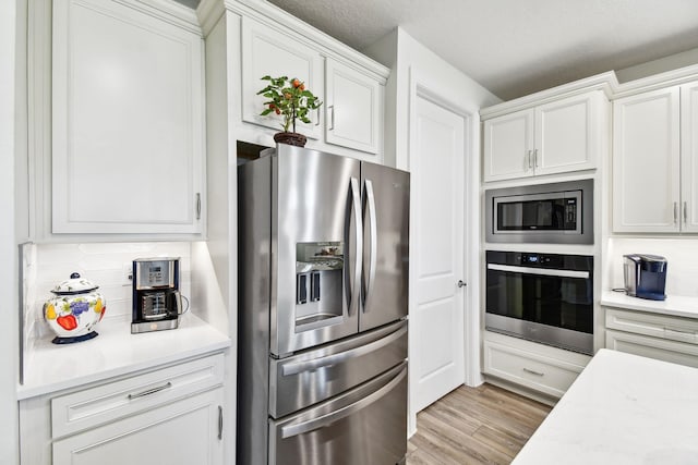 82 Lone Cypress Way, Saint Augustine, FL 32092 - kitchen featuring appliances with stainless steel finishes, light countertops, white cabinetry, light wood-style flooring, and tasteful backsplash