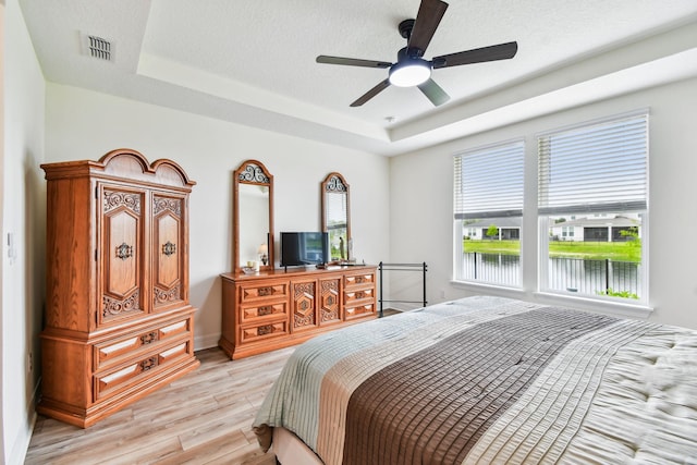 82 Lone Cypress Way, Saint Augustine, FL 32092 - bedroom featuring a raised ceiling, light wood-style flooring, and a ceiling fan