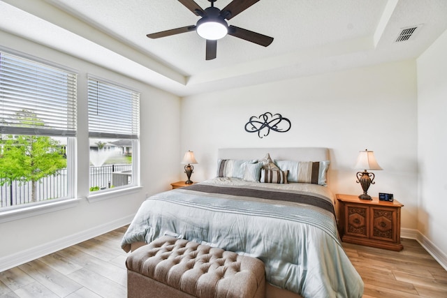 82 Lone Cypress Way, Saint Augustine, FL 32092 - bedroom with multiple windows, a raised ceiling, wood finished floors, and a ceiling fan
