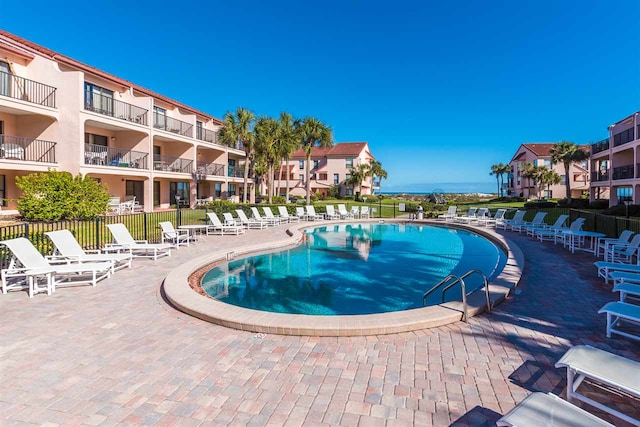 community pool with a patio area and fence