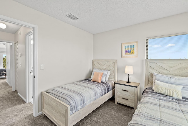 bedroom featuring baseboards, visible vents, carpet floors, and a textured ceiling