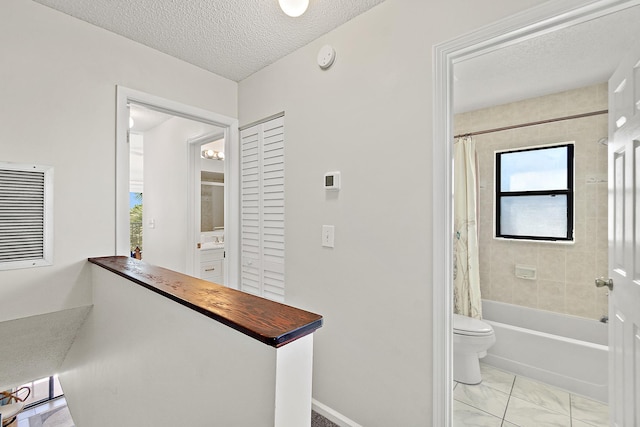 corridor with baseboards and a textured ceiling