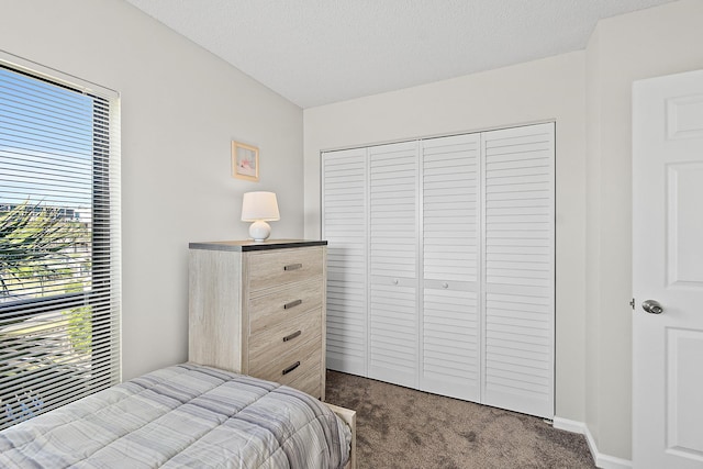 bedroom featuring a closet, dark carpet, and a textured ceiling