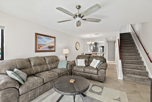 living area with light tile patterned floors, visible vents, stairs, a textured ceiling, and ceiling fan with notable chandelier