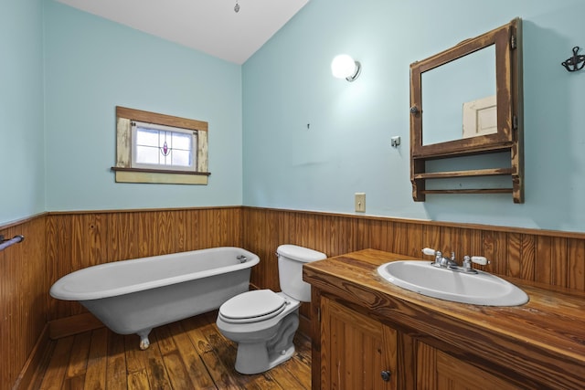 bathroom with hardwood / wood-style floors, vanity, toilet, and a tub to relax in