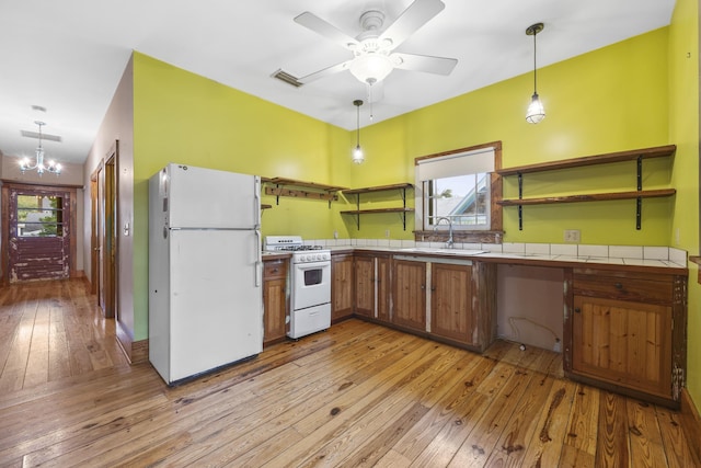 kitchen featuring ceiling fan with notable chandelier, pendant lighting, white appliances, and light wood-type flooring