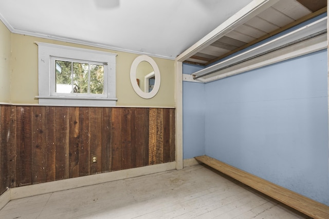 interior space with wood walls, light wood-type flooring, and ornamental molding