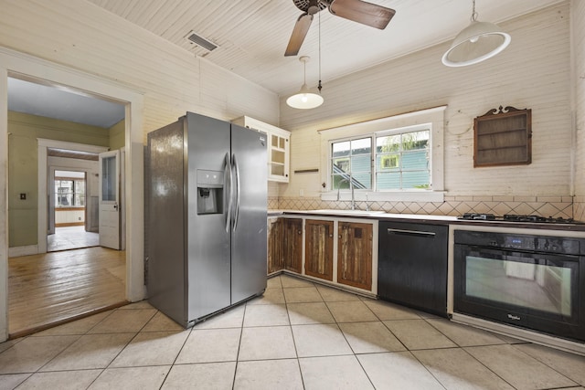 kitchen featuring sink, backsplash, decorative light fixtures, light tile patterned flooring, and black appliances