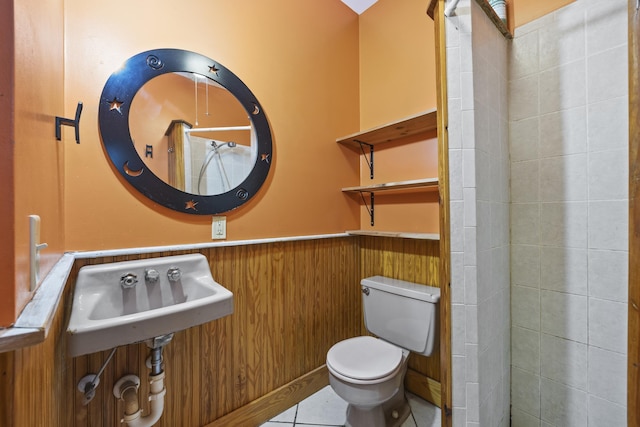 bathroom with tile patterned flooring, toilet, wooden walls, and sink