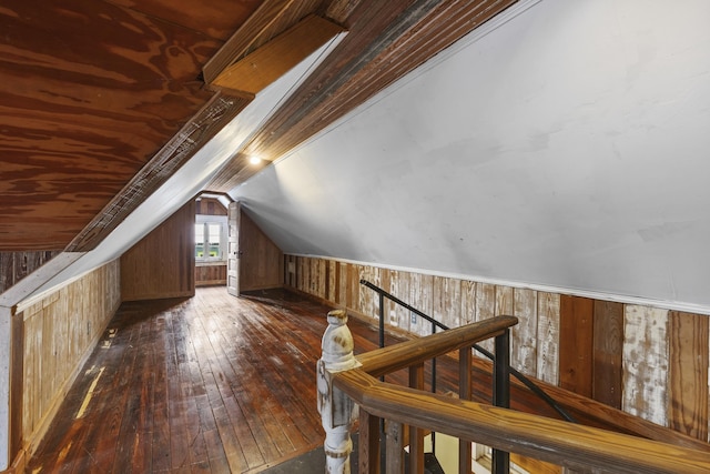 additional living space featuring wood walls, dark hardwood / wood-style flooring, and lofted ceiling