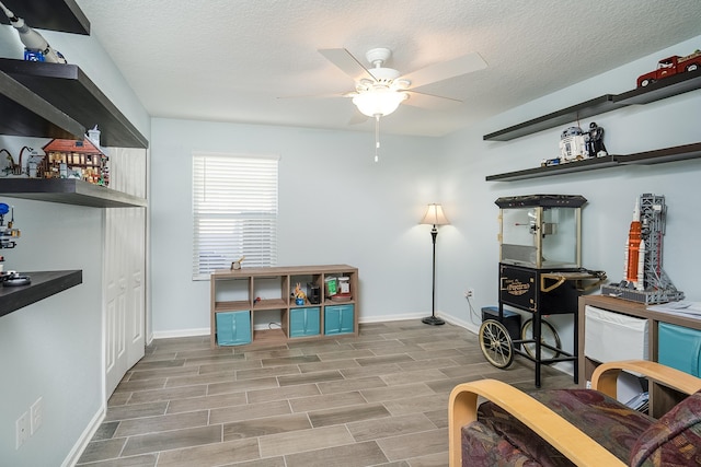 sitting room featuring baseboards, a textured ceiling, a ceiling fan, and wood tiled floor