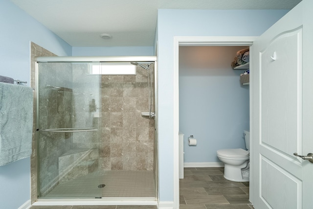 full bathroom featuring a shower stall, toilet, and baseboards