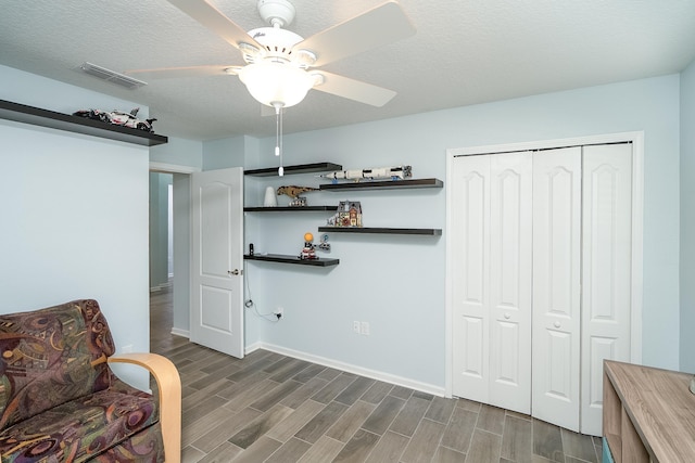 sitting room with ceiling fan, dark hardwood / wood-style floors, and a textured ceiling