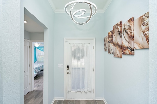 entryway with a chandelier, light hardwood / wood-style floors, and ornamental molding