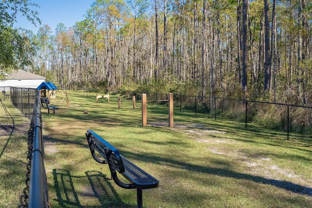 view of community featuring fence, a lawn, and a view of trees