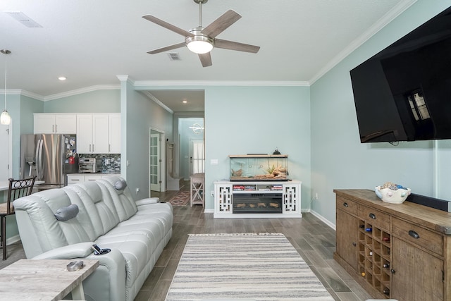 living area featuring visible vents, baseboards, crown molding, and wood finish floors