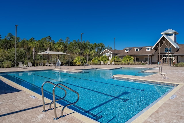 community pool with a patio area and fence