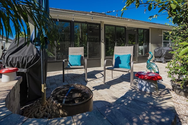 view of patio / terrace with a grill, a fire pit, and a sunroom