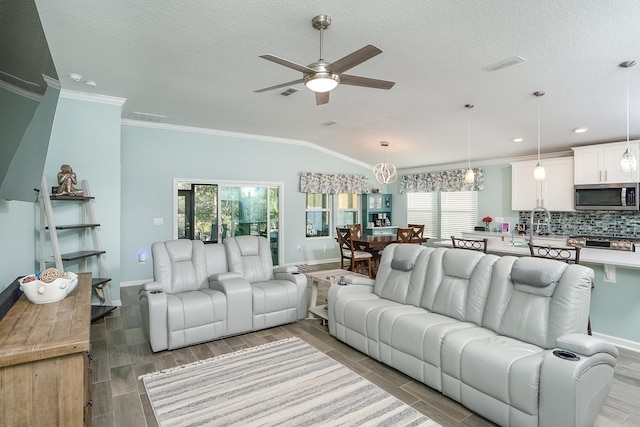 living room featuring ceiling fan with notable chandelier, a healthy amount of sunlight, vaulted ceiling, and ornamental molding