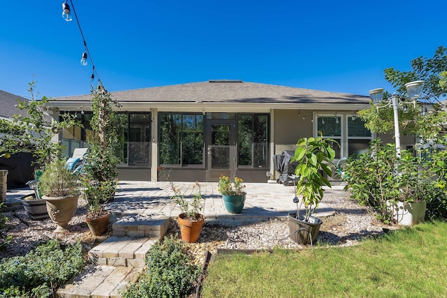 rear view of house with a patio area, stucco siding, and a sunroom