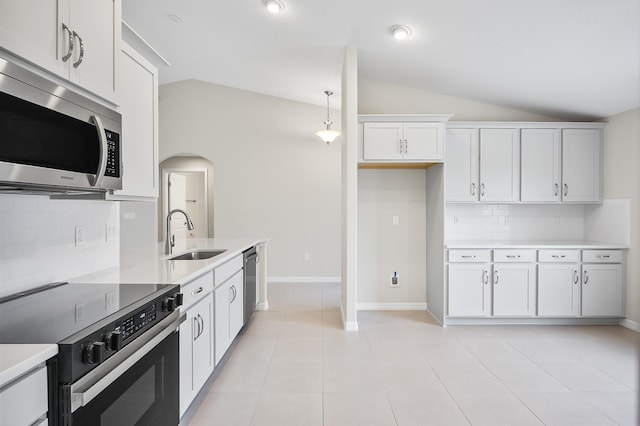 kitchen featuring lofted ceiling, sink, light tile patterned floors, appliances with stainless steel finishes, and white cabinets