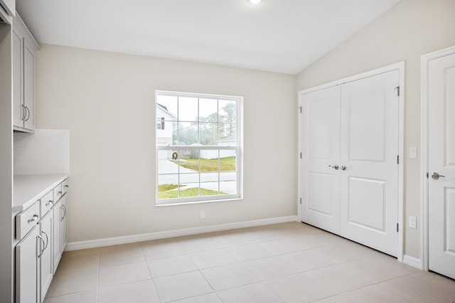 unfurnished bedroom with light tile patterned floors, vaulted ceiling, and a closet