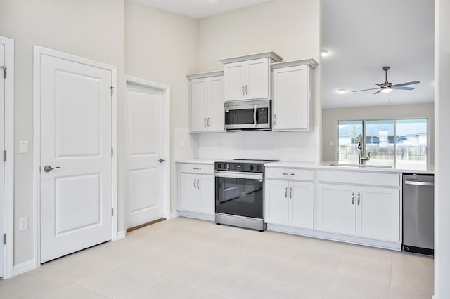 kitchen with sink, white cabinets, backsplash, ceiling fan, and stainless steel appliances