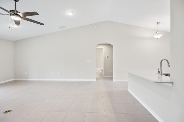 empty room with sink, light tile patterned floors, vaulted ceiling, and ceiling fan