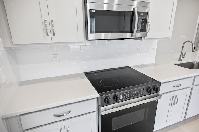 kitchen featuring range with electric cooktop, white cabinetry, sink, and backsplash