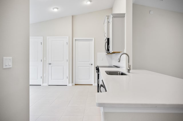 kitchen featuring light tile patterned floors, vaulted ceiling, and sink